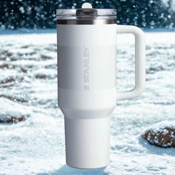 Gourde stanley modèle proflip blanche dans la neige, au milieu de la forêt