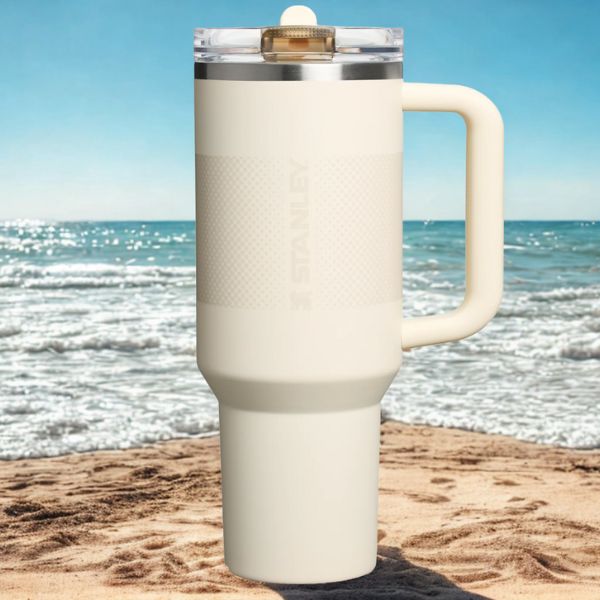 Gourde stanley modèle proflip dans le sable, au bord de mer